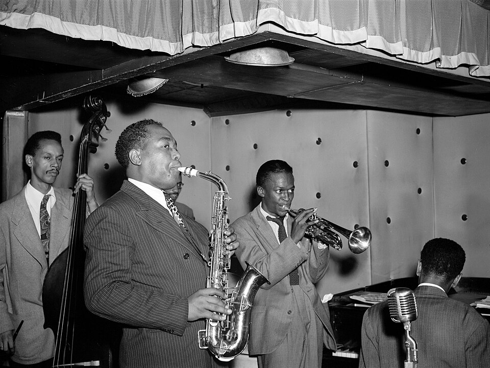 Jazz musicians performing at a nightclub, with Parker on saxophone and Davis nearby|