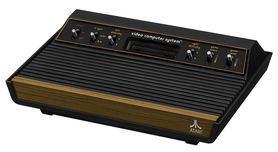 A woodgrain-fronted Atari 2600 console with six front switches and a single cartridge slot.