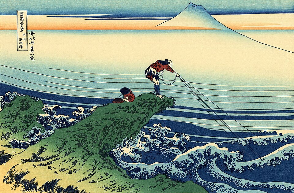 Fisherman on a rocky promontory with Mount Fuji beyond