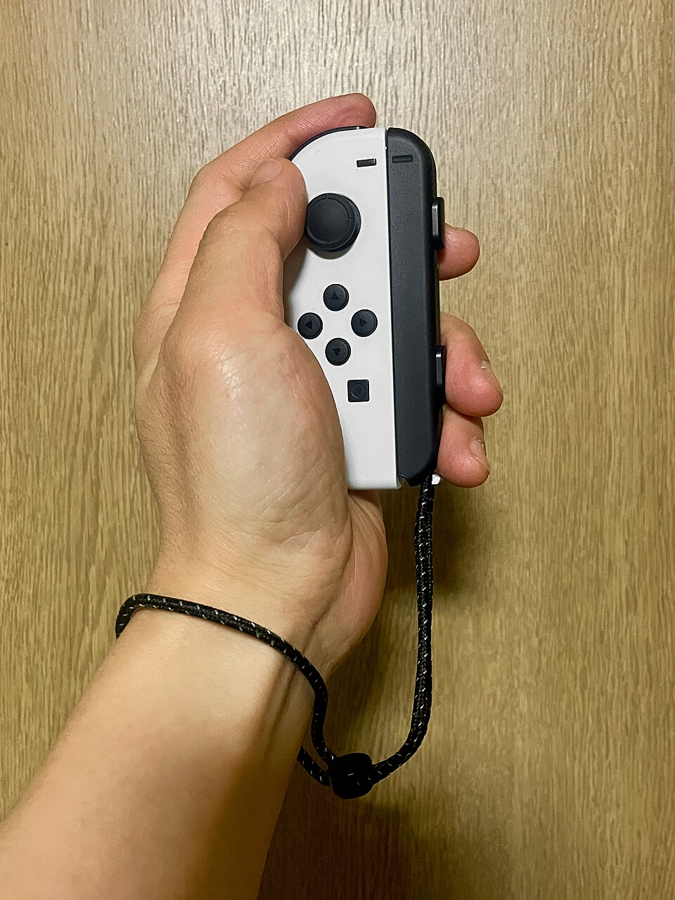 A small detachable game controller with a wrist strap attached.