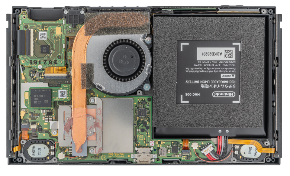 Opened console interior with a large black battery, circuit board, and cooling fan.