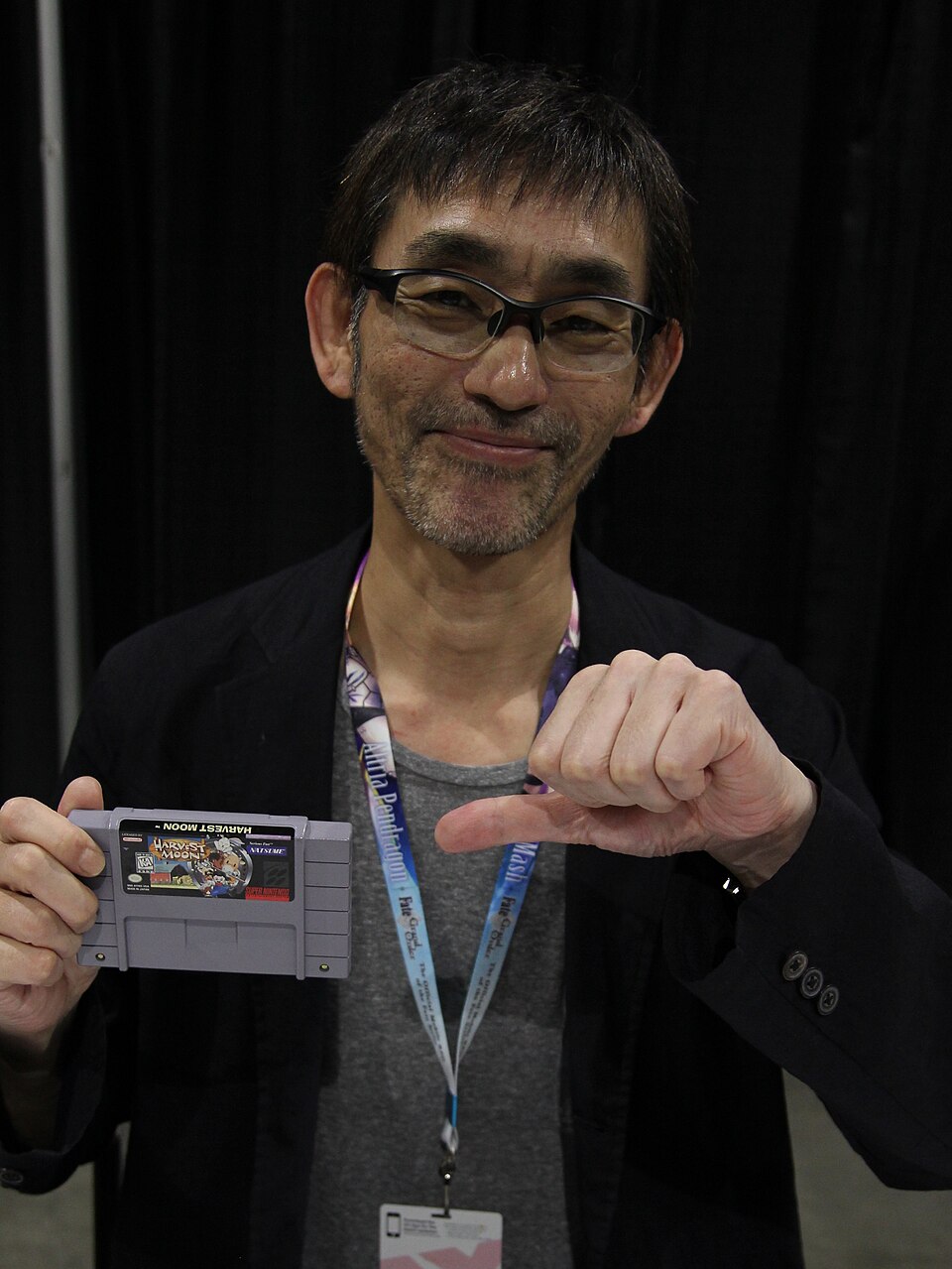 Yasuhiro Wada holding up a Super Nintendo cartridge for Harvest Moon|