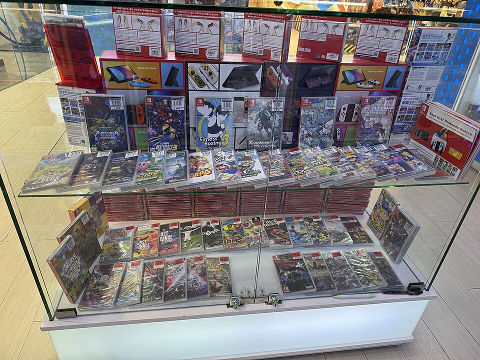 A store display case of boxed handheld consoles and games.